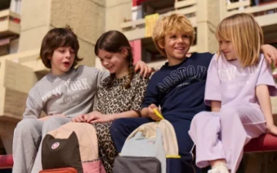 Quatre enfants portant des tenues Kiabi tendance pour la rentrée des classes 2025, avec sacs à dos colorés
