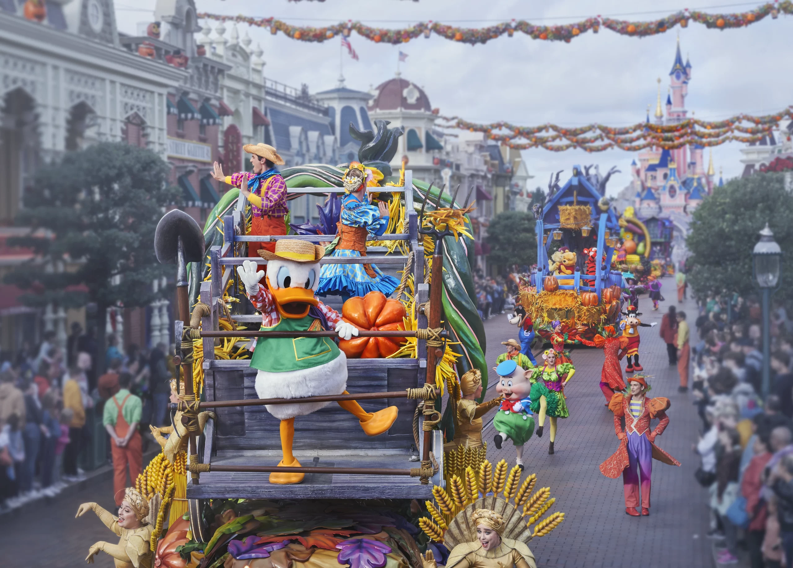 Donald Duck en costume fermier sur un char décoré de citrouilles lors de la parade d’Halloween 2025 à Disneyland Paris sur Main Street U.S.A, avec le Château de la Belle au Bois Dormant en arrière-plan.