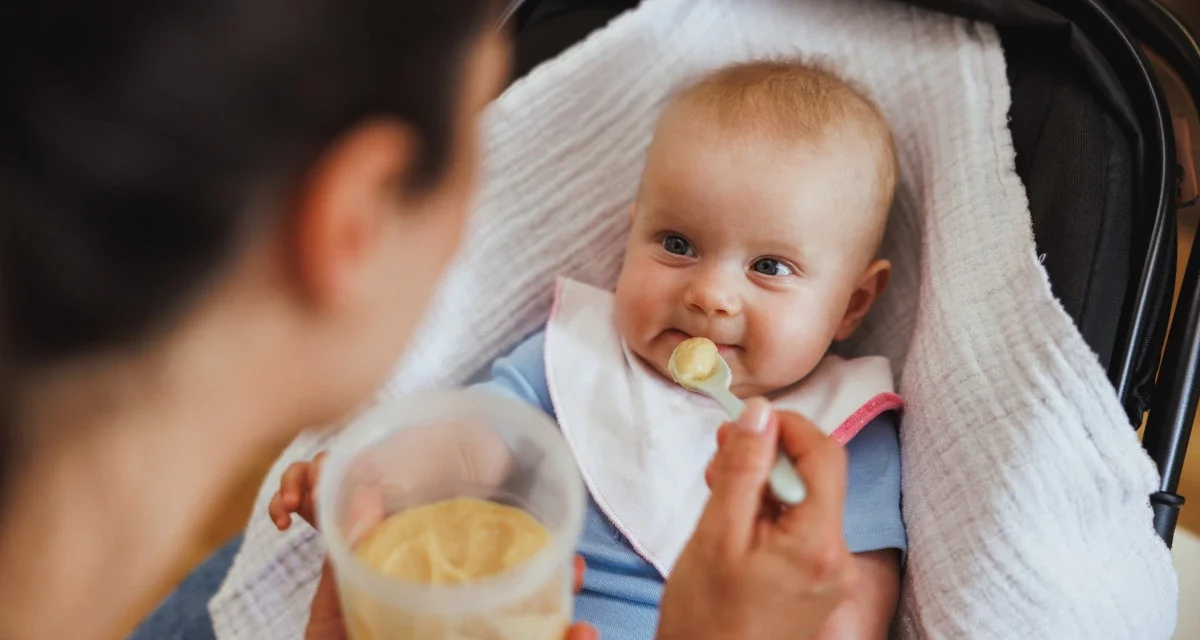 Bébé de 6 à 12 mois mangeant une purée avec l’aide de sa maman