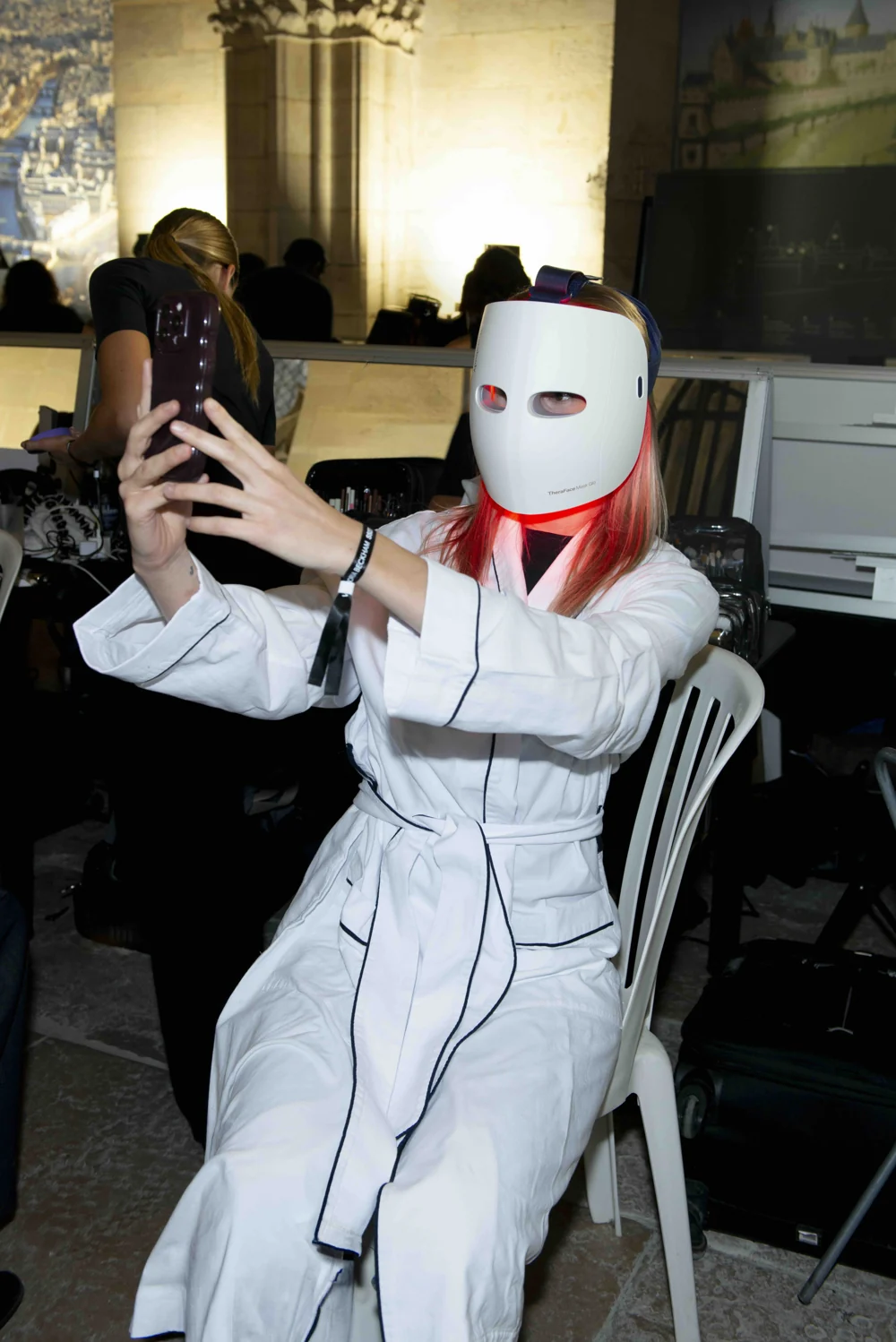 Un mannequin porte le masque LED TheraFace Mask Glo dans les coulisses du défilé Victoria Beckham